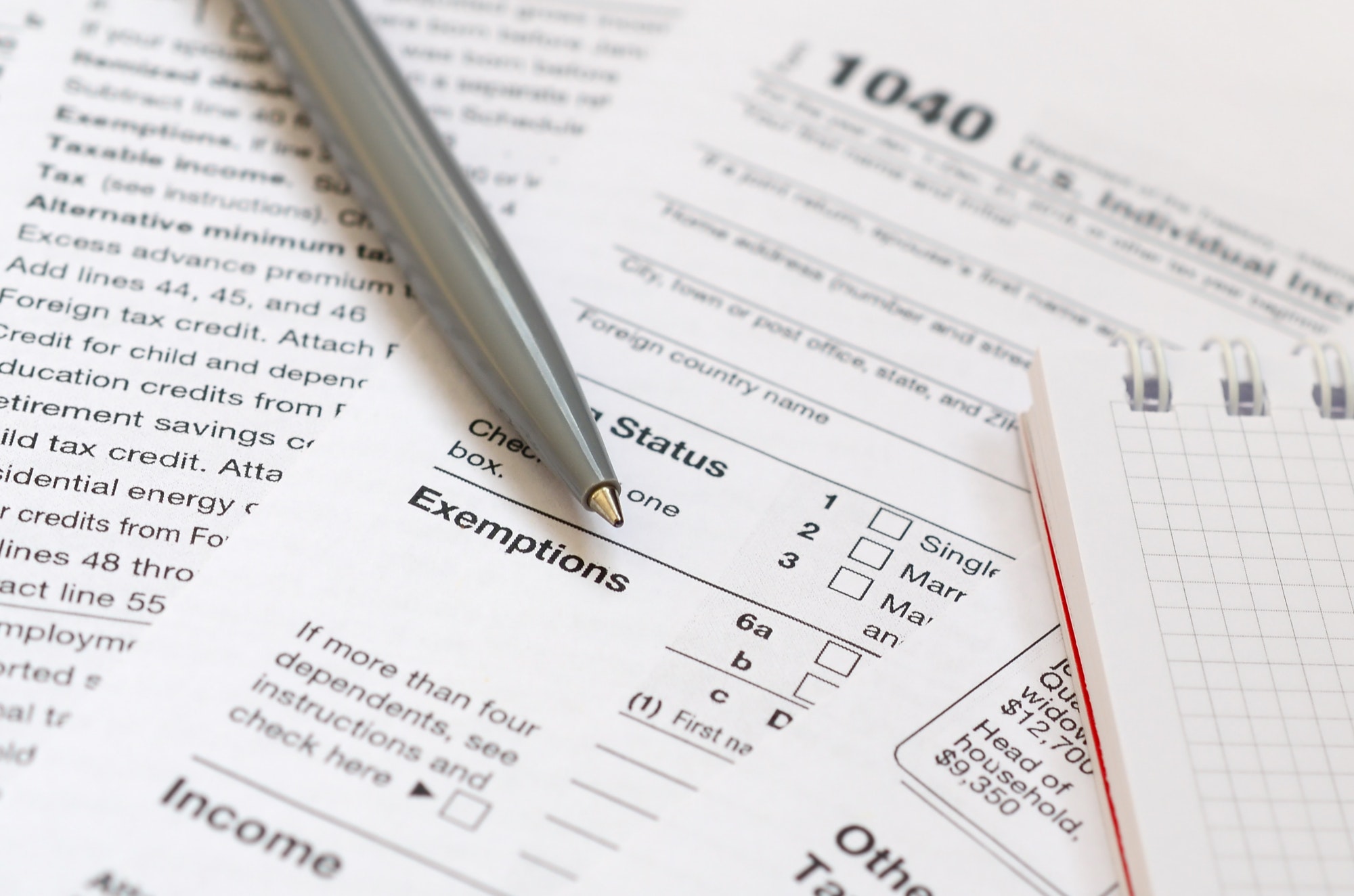 The pen and notebook is lies on the tax form 1040 U